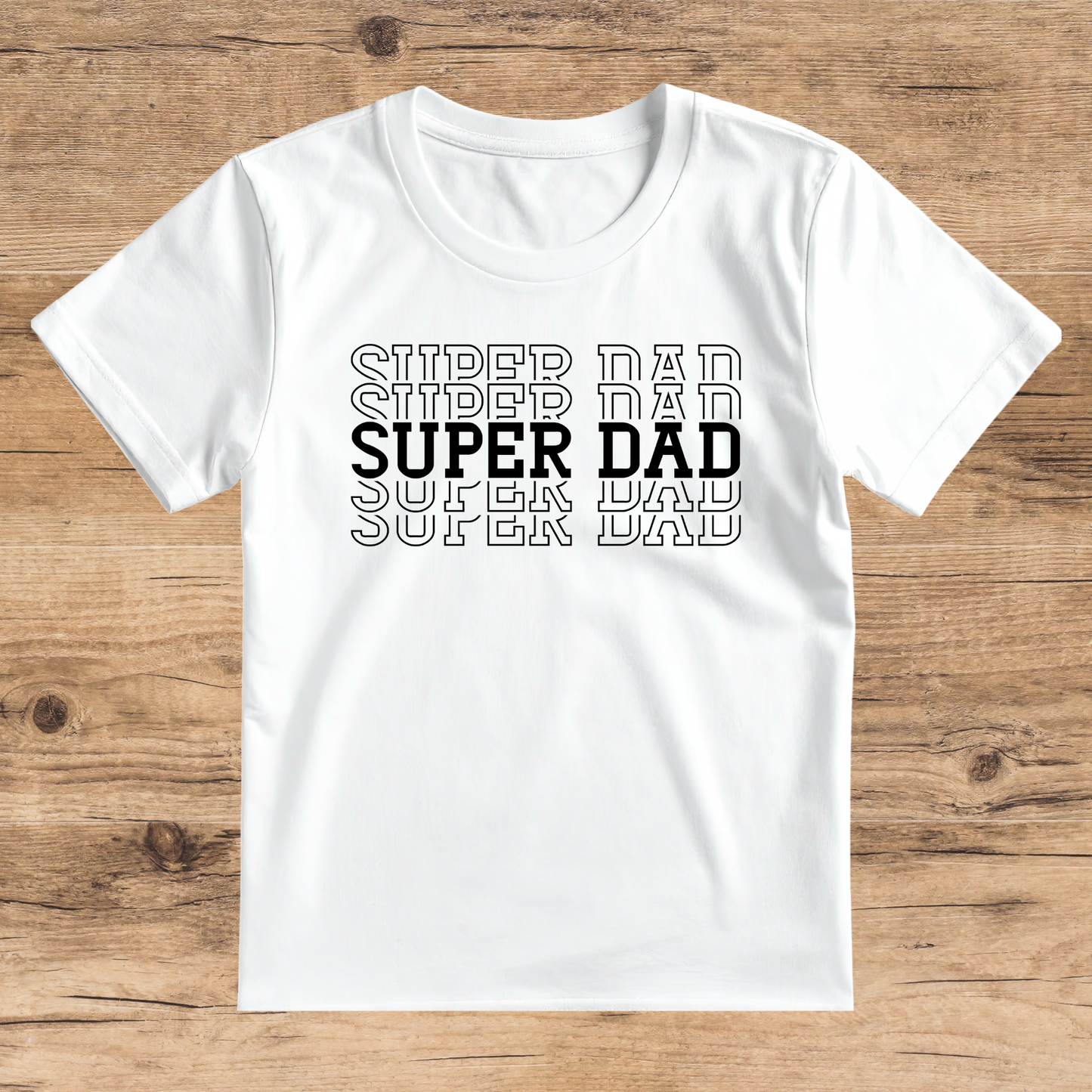 White t-shirt with 'SUPER DAD' text on a wooden surface