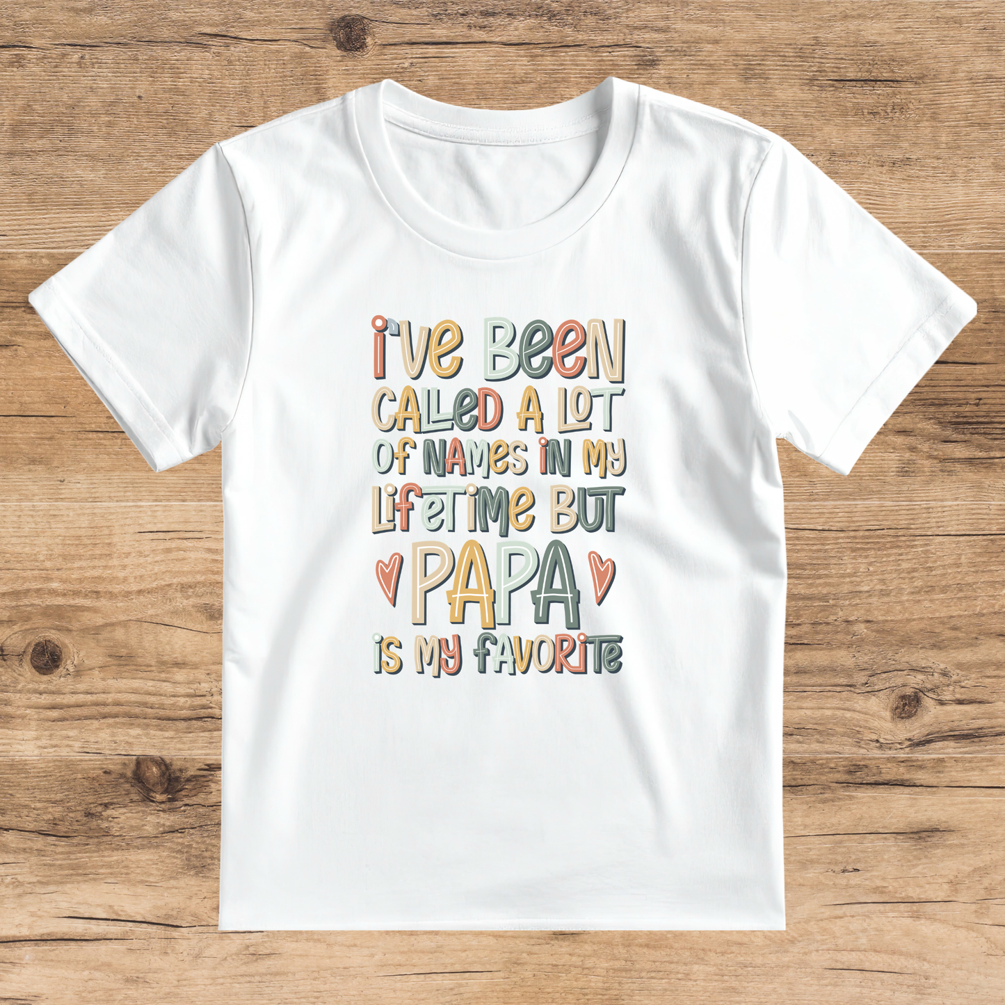 White t-shirt with colorful text on a wooden surface