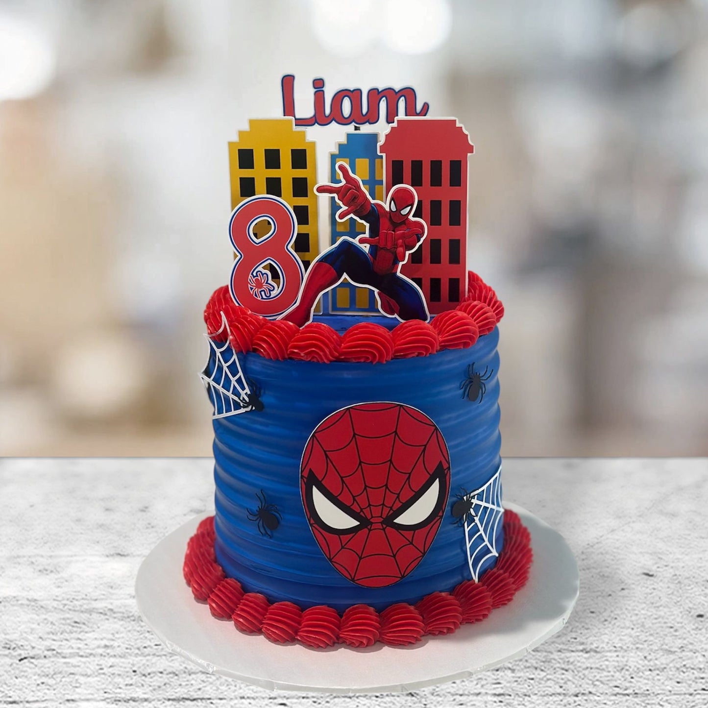 Spider-Man themed birthday cake with cityscape topper on a wooden table