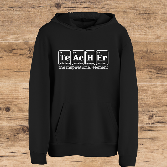 Black hoodie with 'Teacher the inspirational element' text on a wooden background
