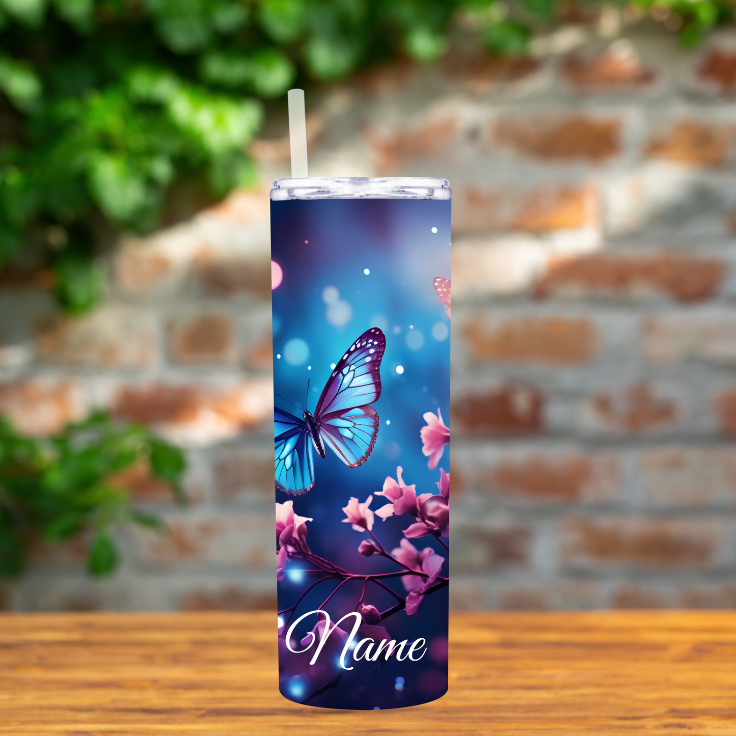 Tumbler with butterfly and floral design on a wooden surface with a brick wall background