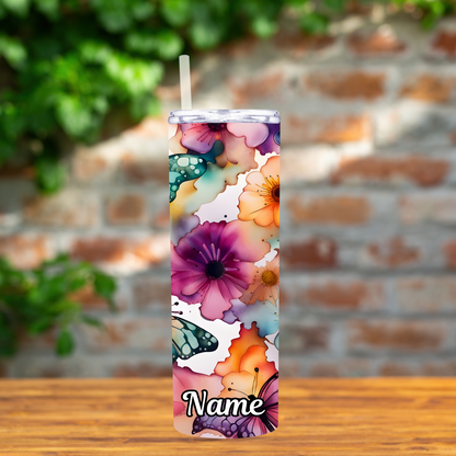 Tumbler with floral design and 'Name' text on a wooden surface with a brick wall background