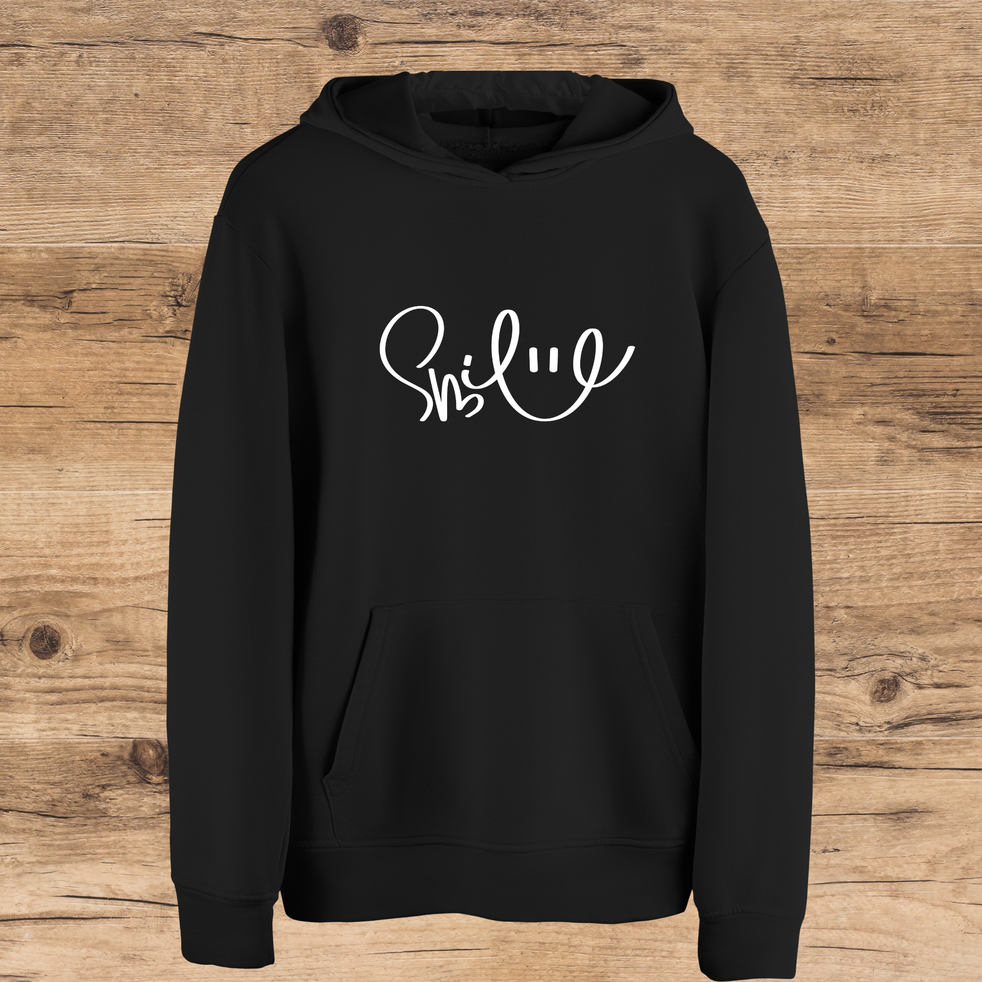Black hoodie with 'Smile' text on a wooden surface