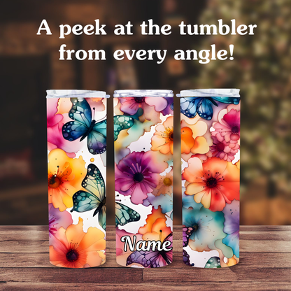Three colorful tumblers with floral and butterfly design on a wooden surface.