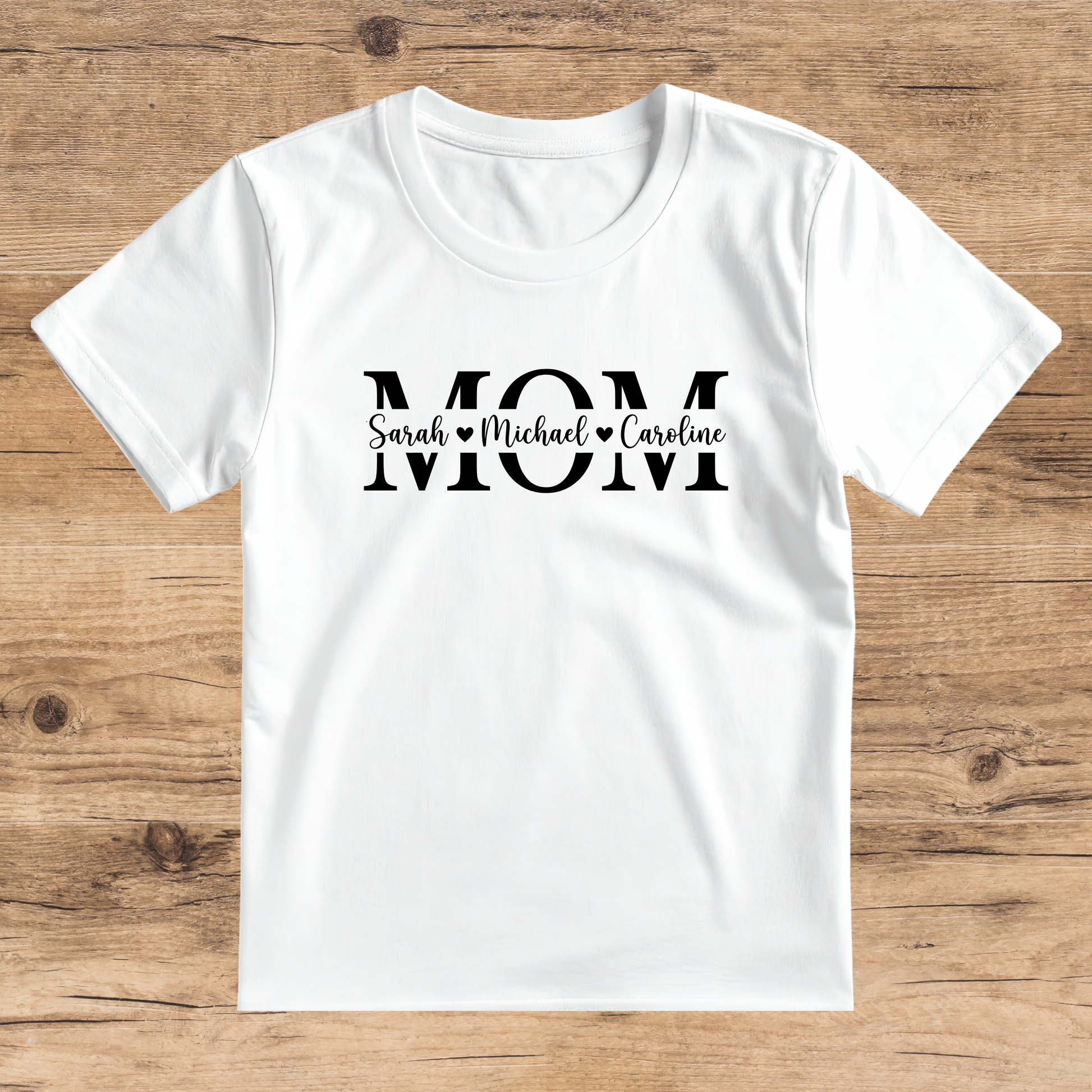 White t-shirt with 'Mom' text on a wooden surface