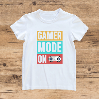 White t-shirt with 'Gamer Mode On' text design on a wooden surface