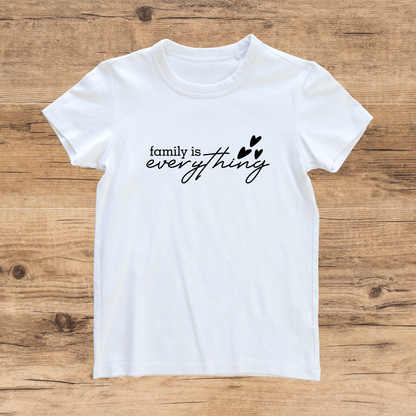White t-shirt with 'family is everything' text on a wooden surface