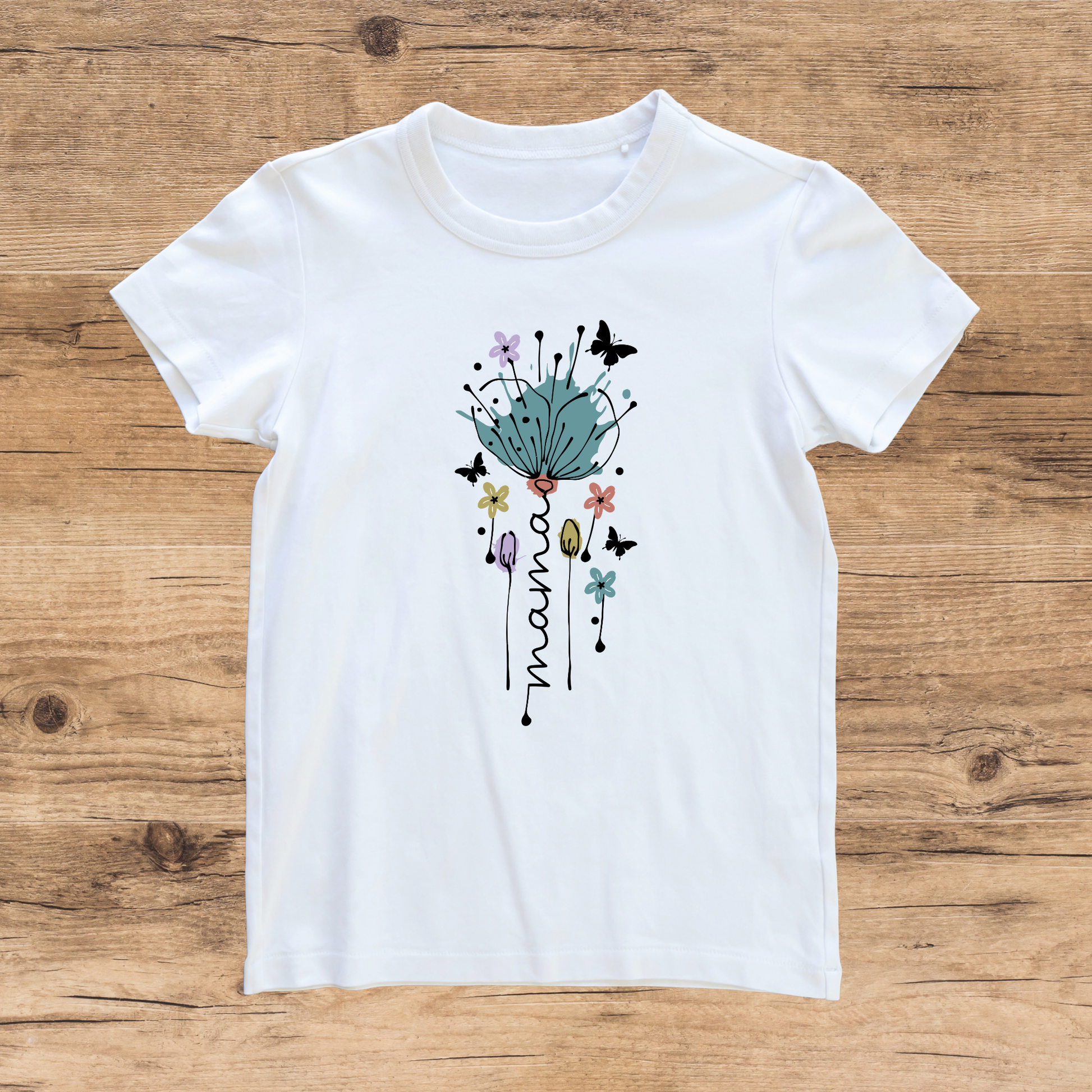 White t-shirt with floral design and 'mama' text on a wooden surface