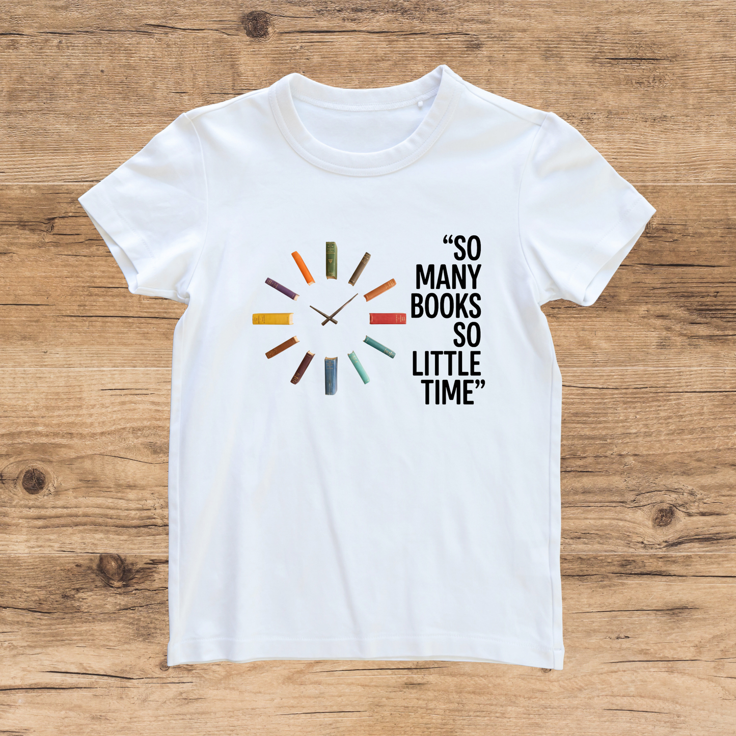 White t-shirt with book-themed design and text on a wooden surface