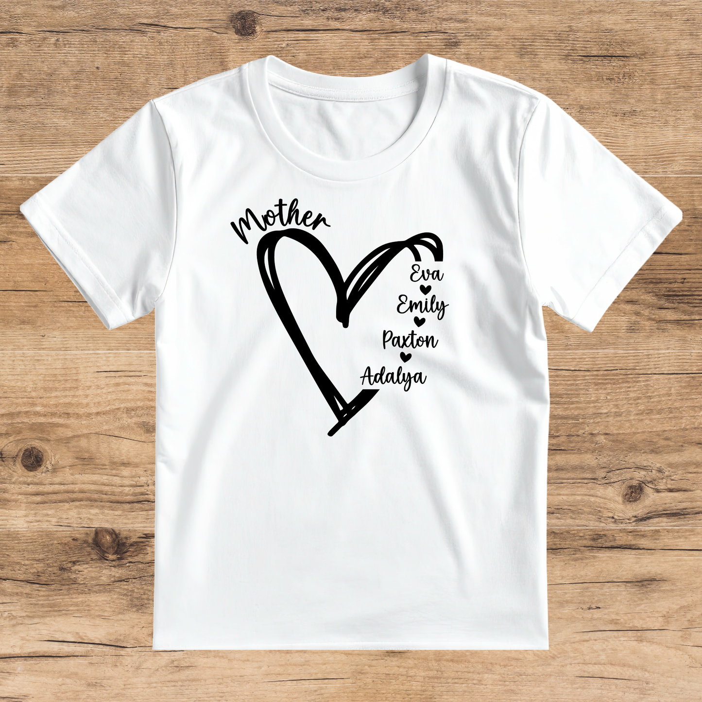 White t-shirt with black heart design and names on a wooden surface