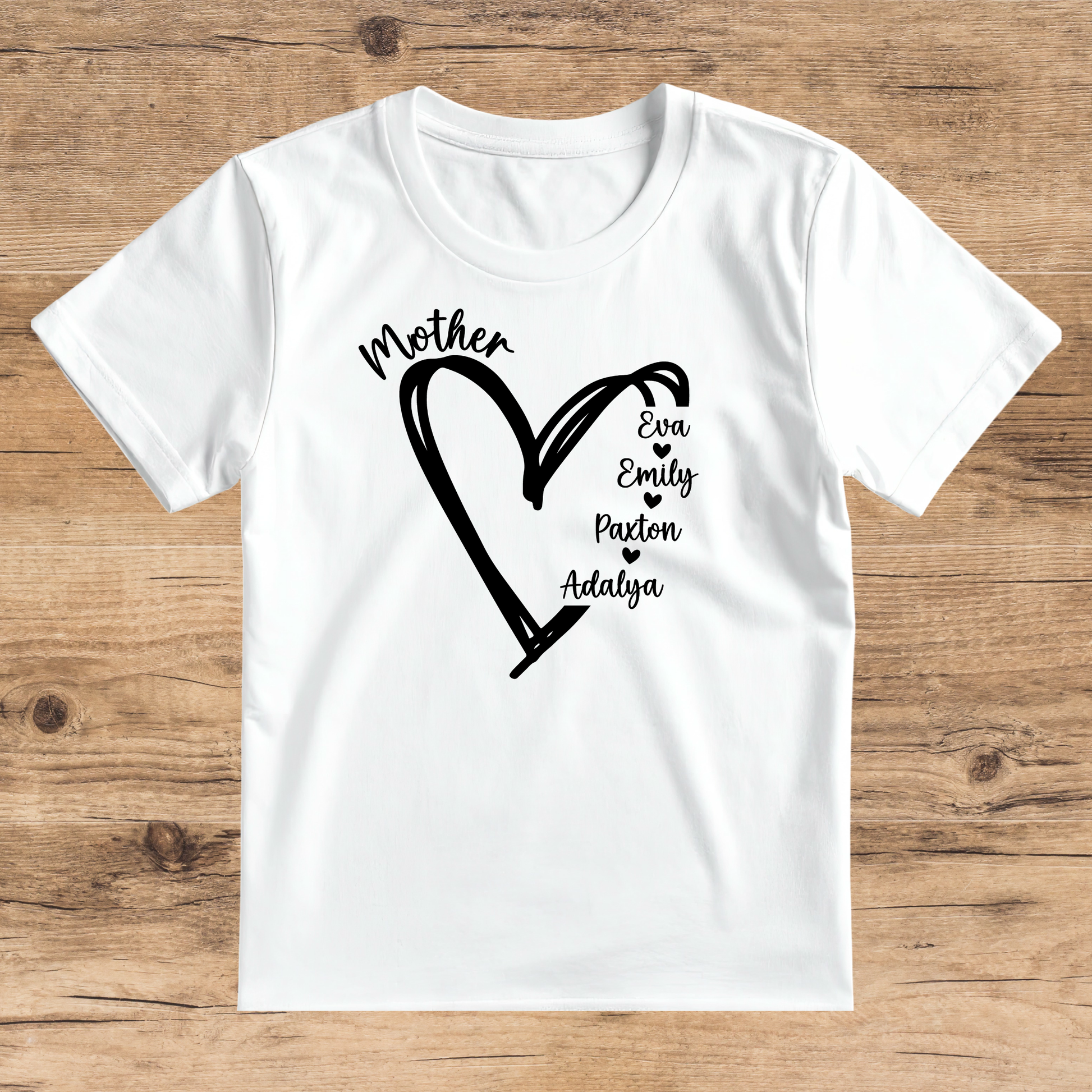 White t-shirt with black heart design and names on a wooden surface