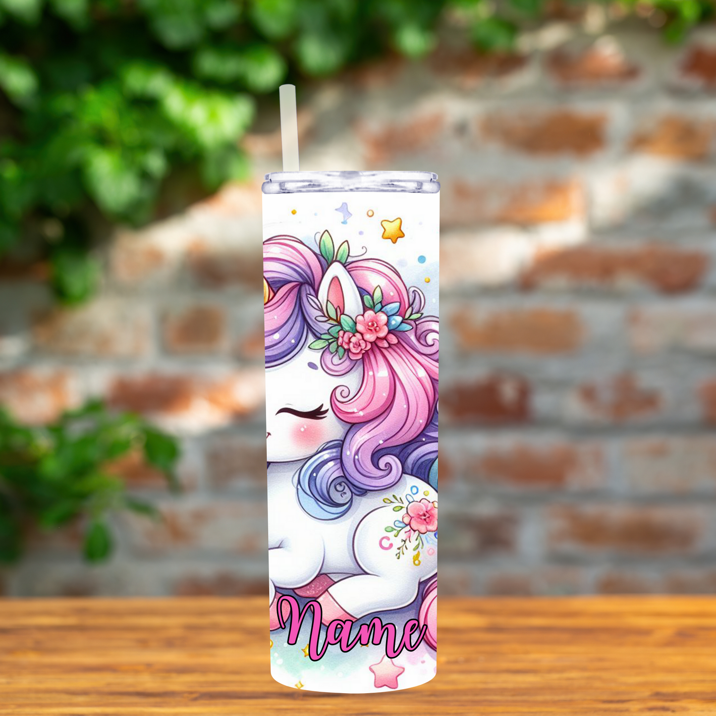 Tumbler with unicorn design on a wooden surface with a brick wall background