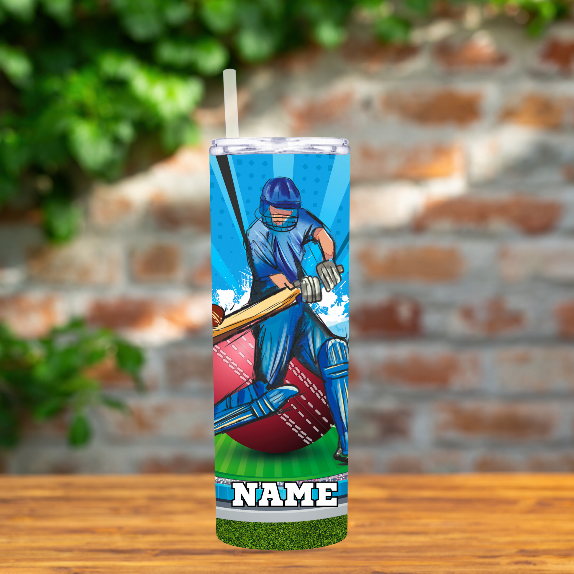 Tumbler with a cricket player design on a wooden surface with a brick wall background