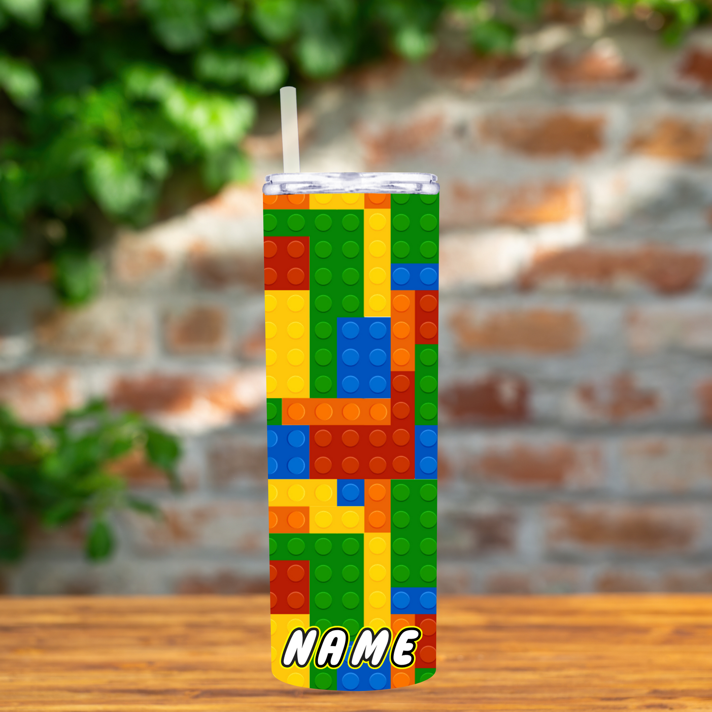 Tumbler with colorful block pattern on a wooden surface with a blurred brick wall background