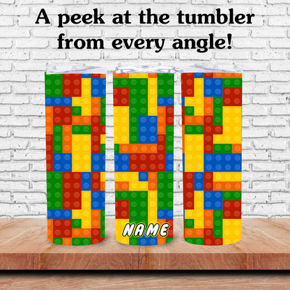 Colorful tumblers with block design on a wooden surface against a white brick wall.