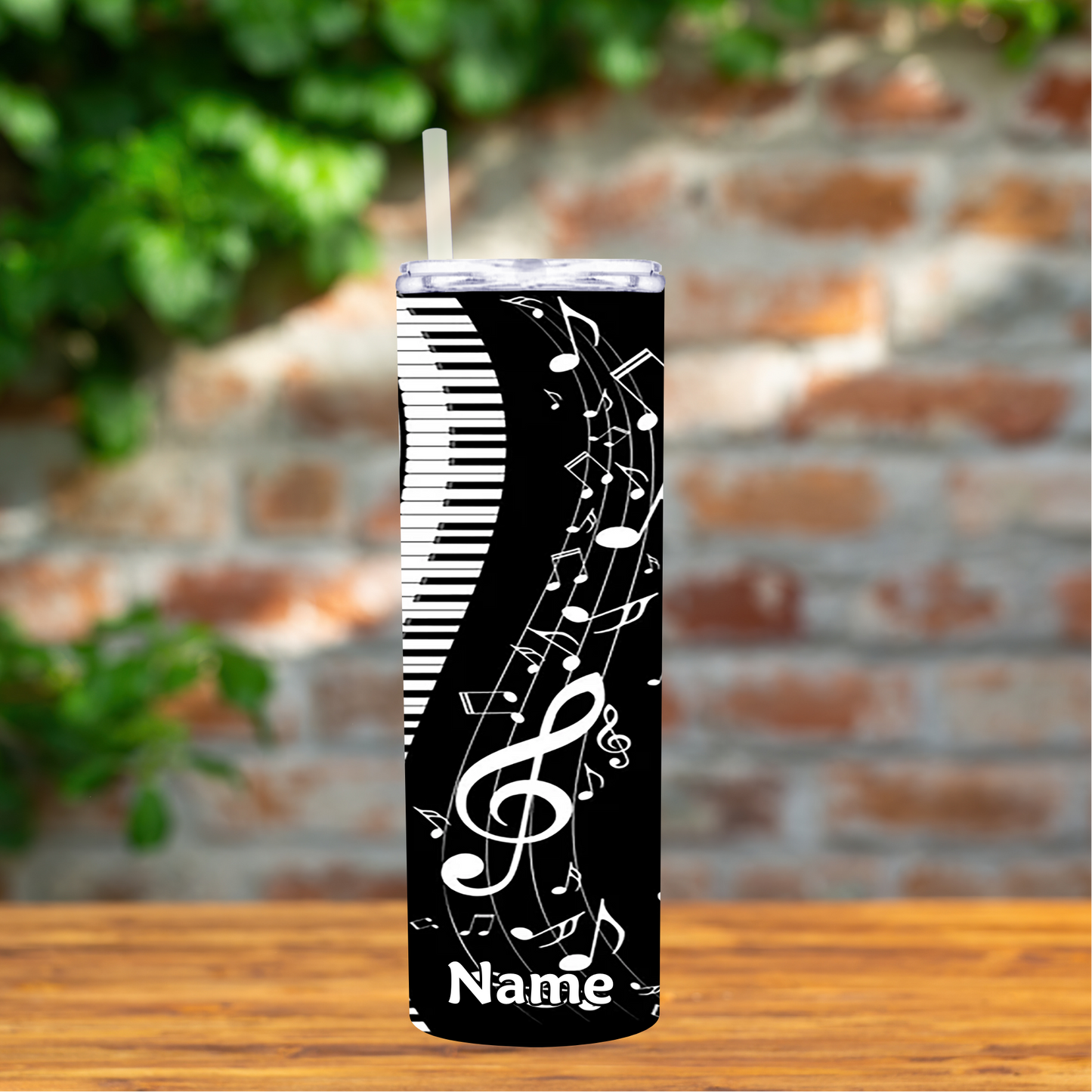 Tumbler with musical design and 'Name' text on a wooden surface with a brick wall background