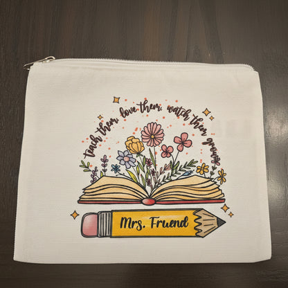 White pouch with an open book, flowers, and a pencil design