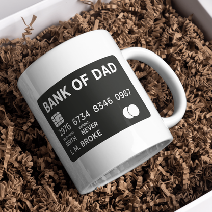 White mug with 'Bank of Dad' design on a bed of brown crinkled paper