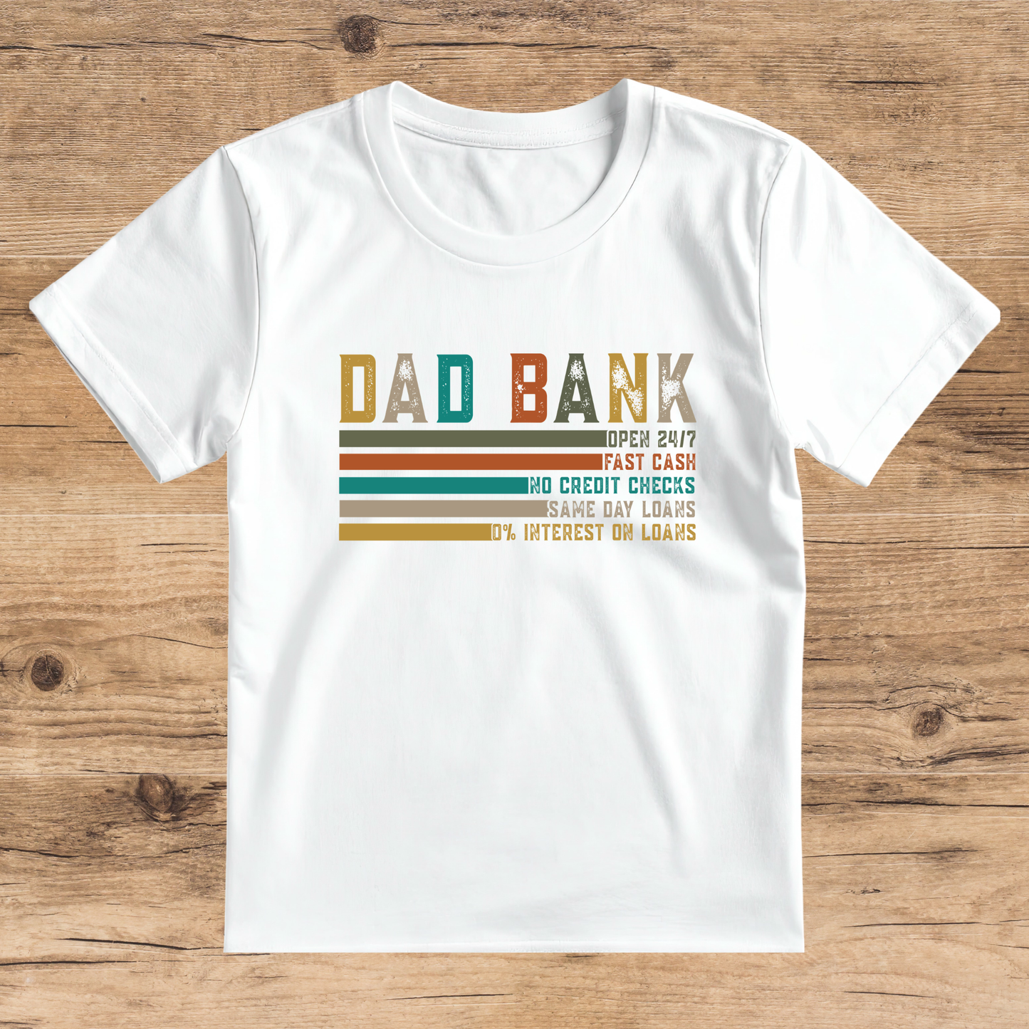 White t-shirt with colorful text design on a wooden surface