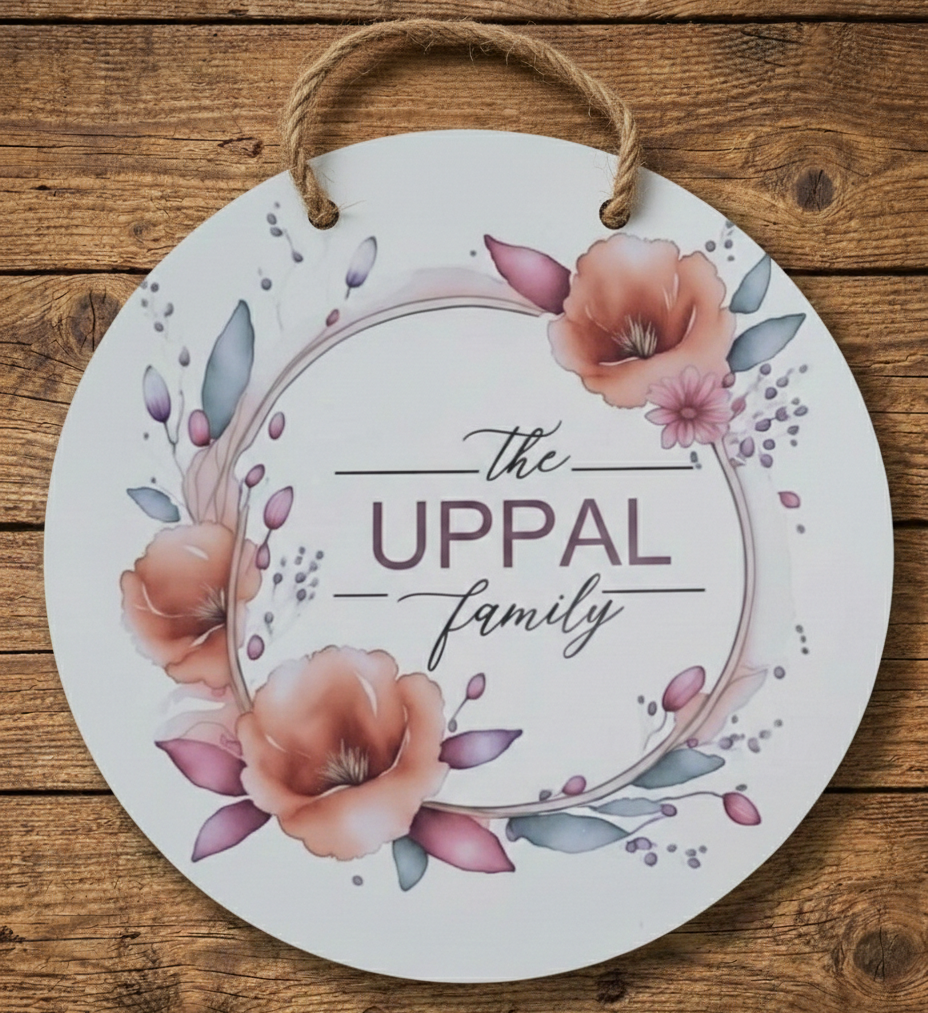 Round decorative sign with floral design and 'The Uppal Family' text on a wooden background
