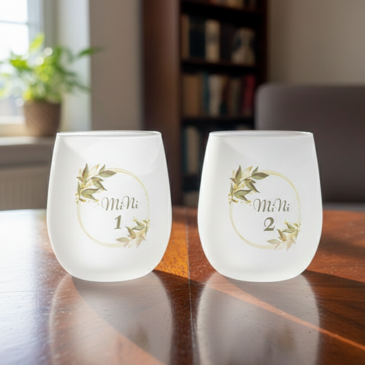 Two frosted wine glasses with custom decorative labels.