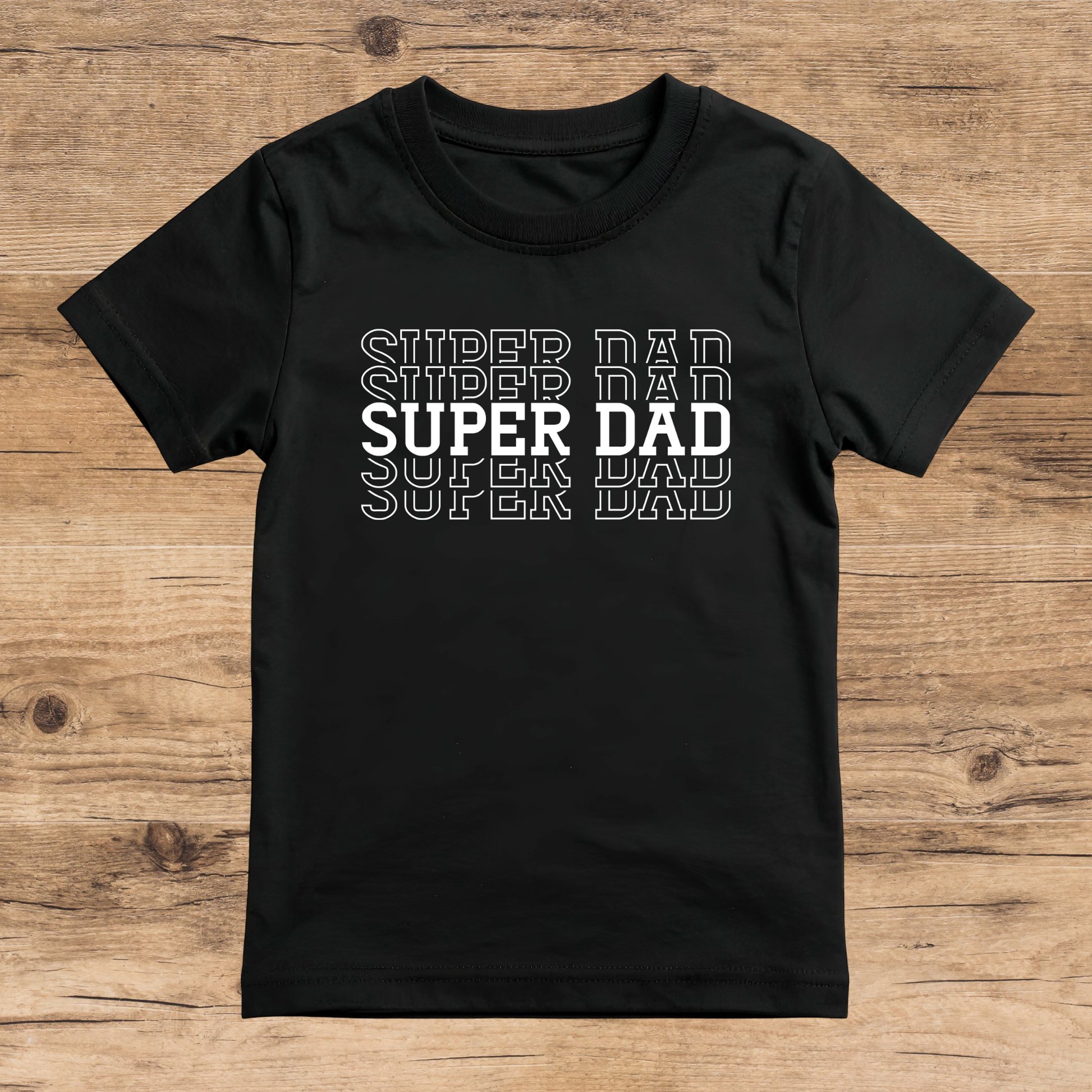 Black t-shirt with 'Super Dad' text on a wooden surface