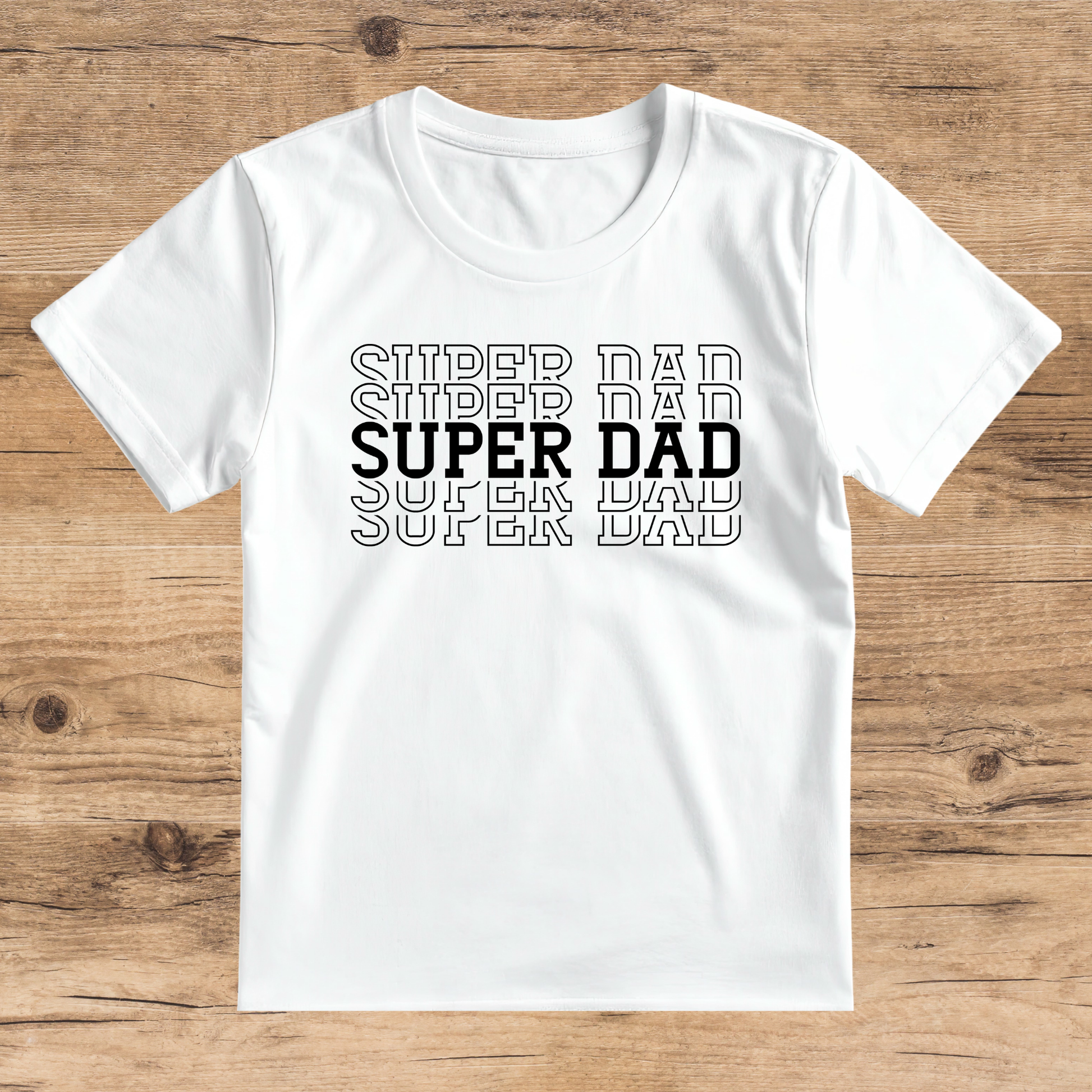 White t-shirt with 'SUPER DAD' text on a wooden surface