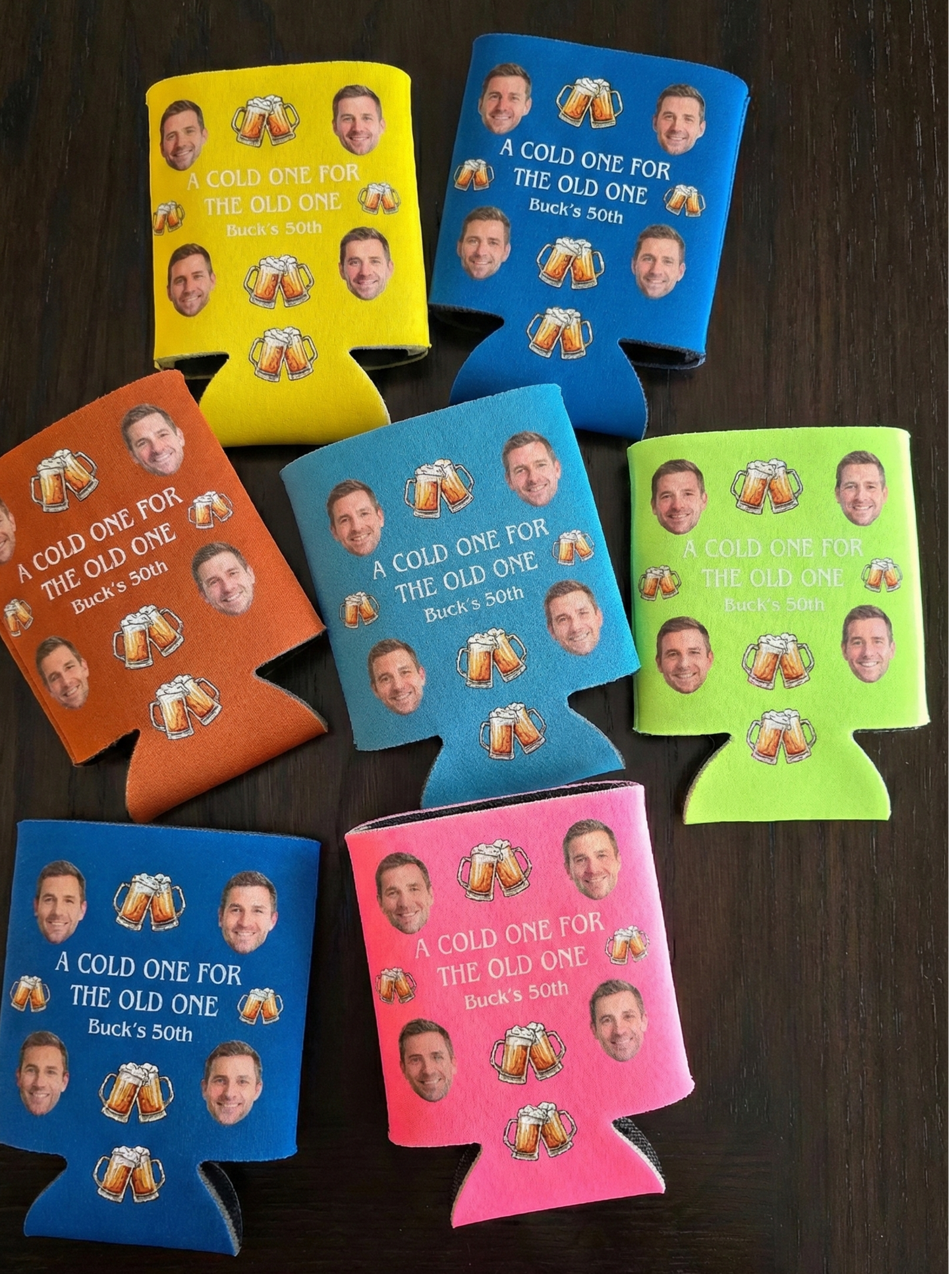 Colorful can coolers with printed faces and text on a wooden surface