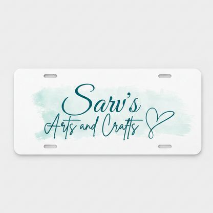 A white novelty license plate with rounded corners, featuring a light blue watercolor wash background and teal script text that reads 'Sarv's Arts and Crafts' with a heart outline.