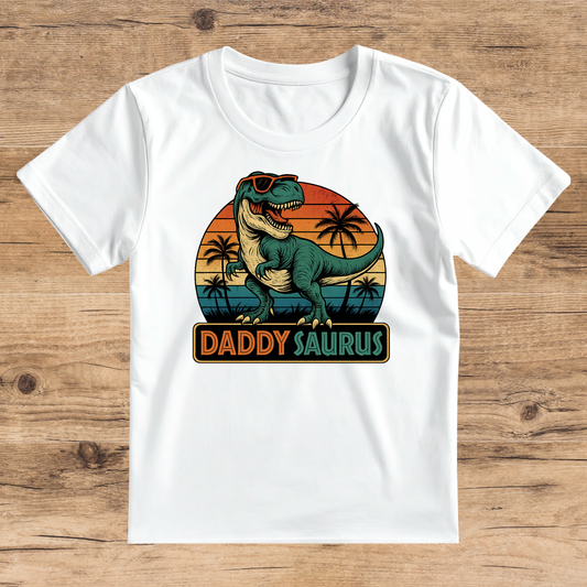 White t-shirt with a dinosaur graphic and 'DADDYSAURUS' text on a wooden surface