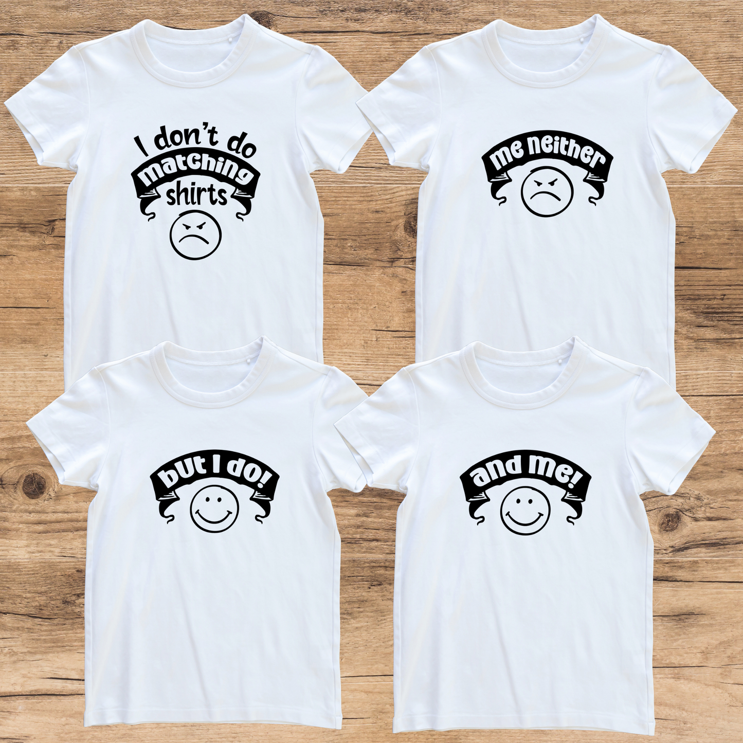 Four white t-shirts with black text and smiley face graphics on a wooden surface
