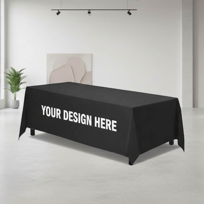 Black tablecloth with 'Your Design Here' text in a modern room with large windows and minimal decor.