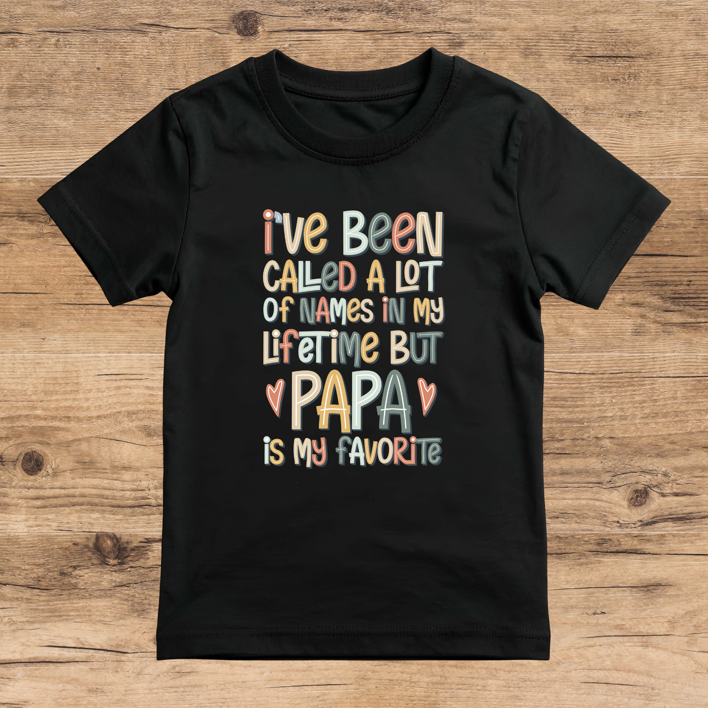 Black t-shirt with colorful text on a wooden surface