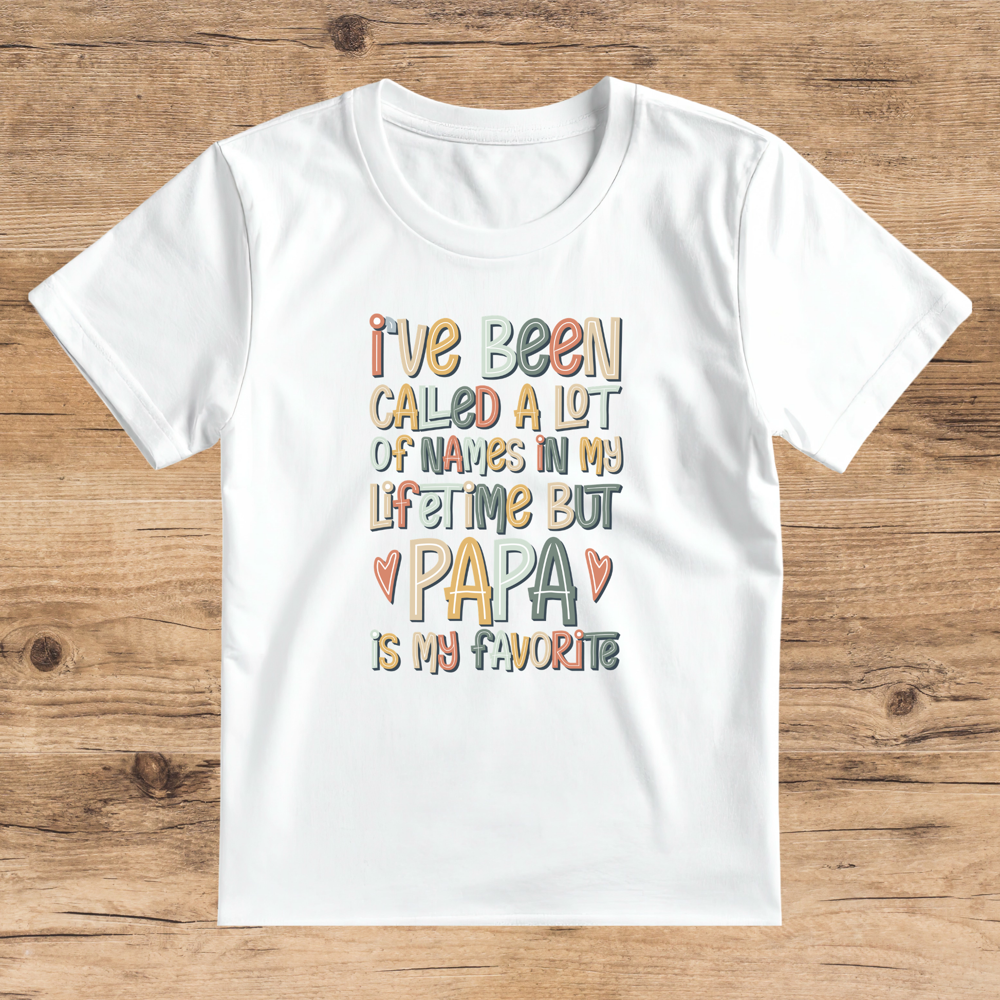 White t-shirt with colorful text on a wooden surface