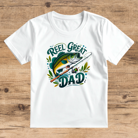 White t-shirt with 'Reel Great Dad' graphic on a wooden surface
