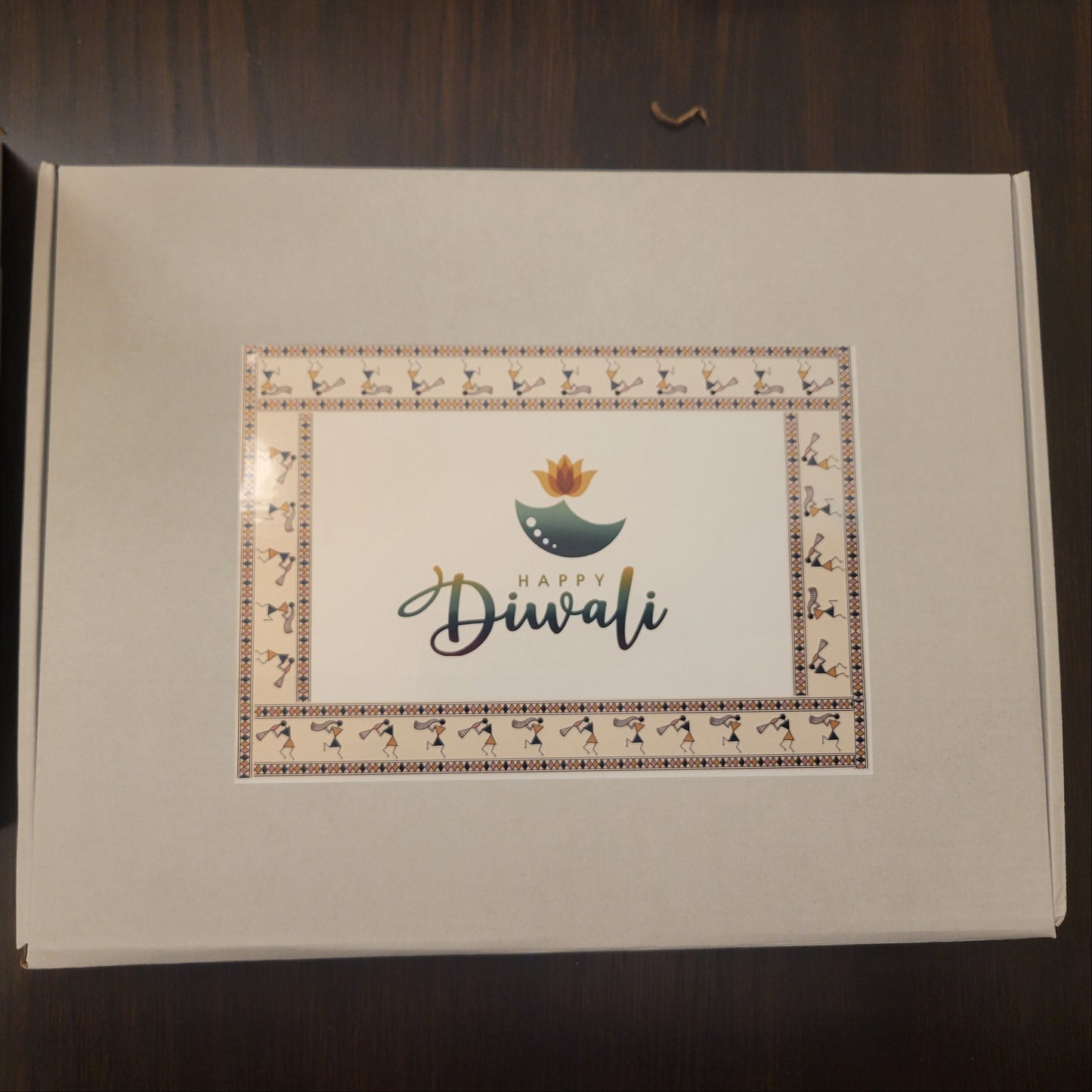 Box with 'Happy Diwali' card on a wooden surface