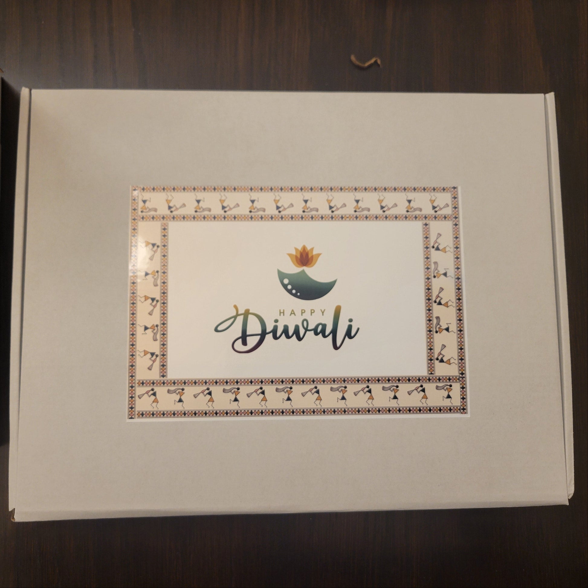 Box with 'Happy Diwali' card on a wooden surface
