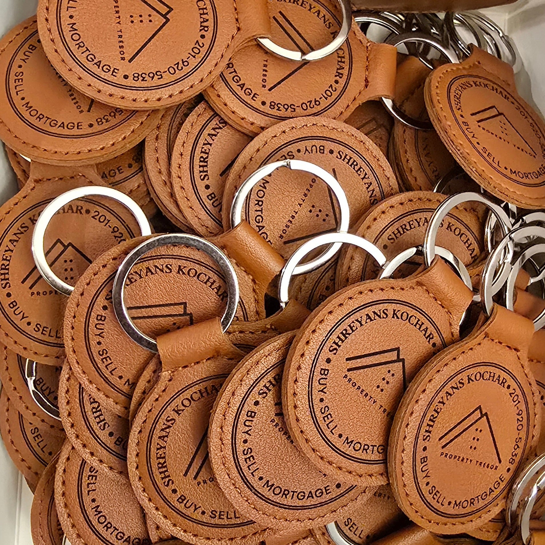 Collection of brown leather keychains with engraved text on a white background