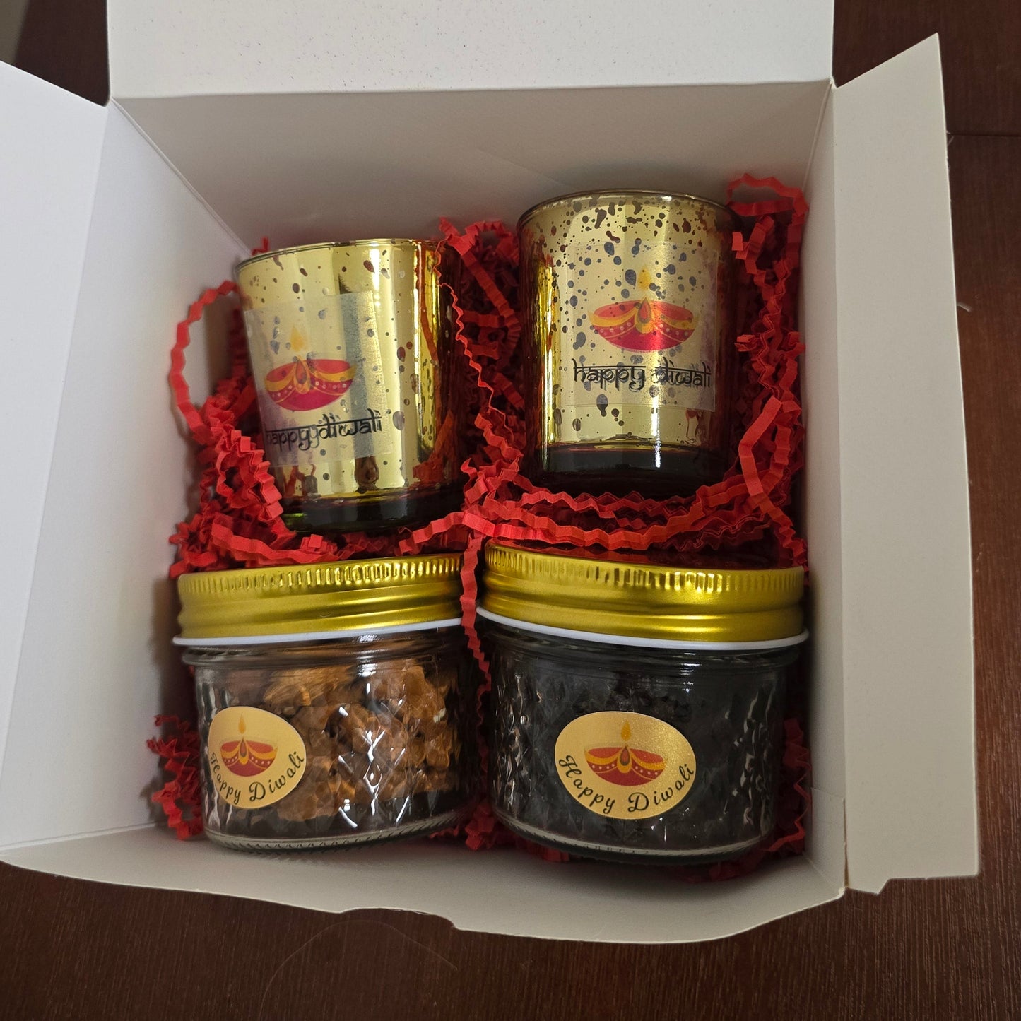 Three small jars with gold lids in a white box on a wooden surface