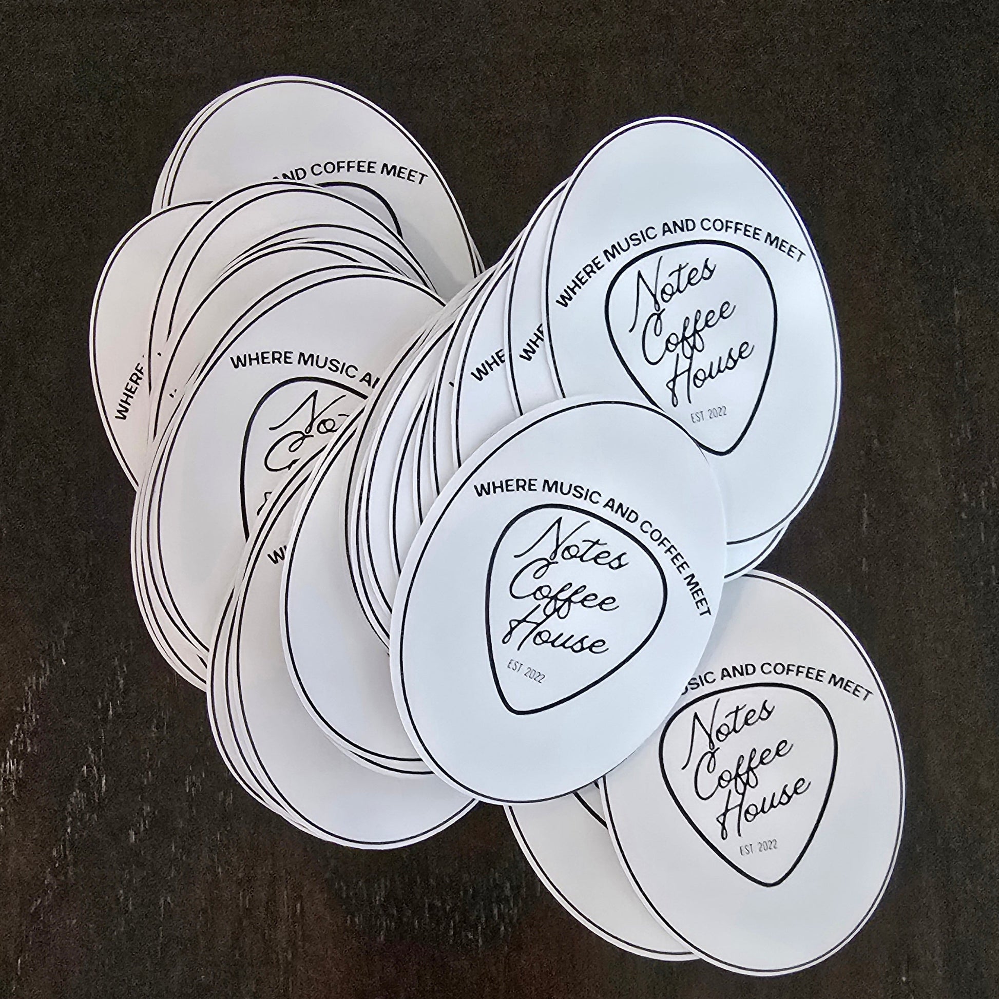 Stickers with 'Notes Coffee House' text on a dark surface