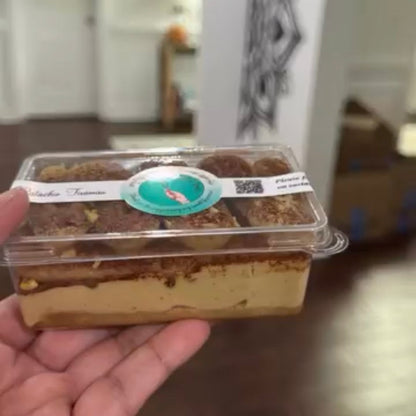 Hand holding a packaged dessert with a blurred indoor background