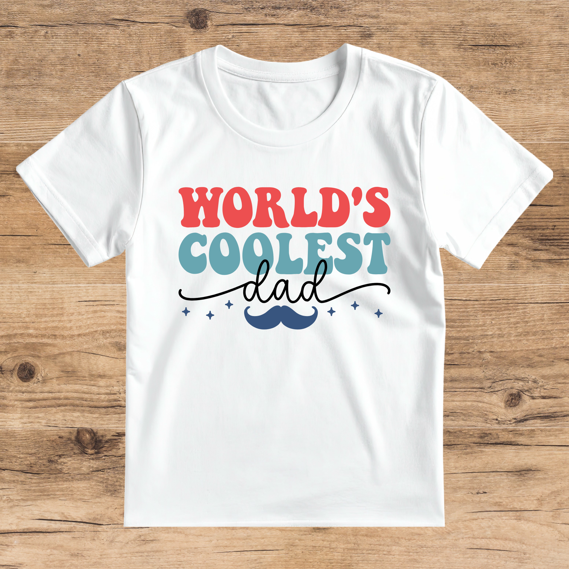 White t-shirt with 'World's Coolest Dad' text on a wooden surface