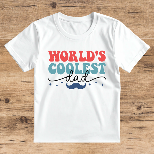 White t-shirt with 'World's Coolest Dad' text on a wooden surface